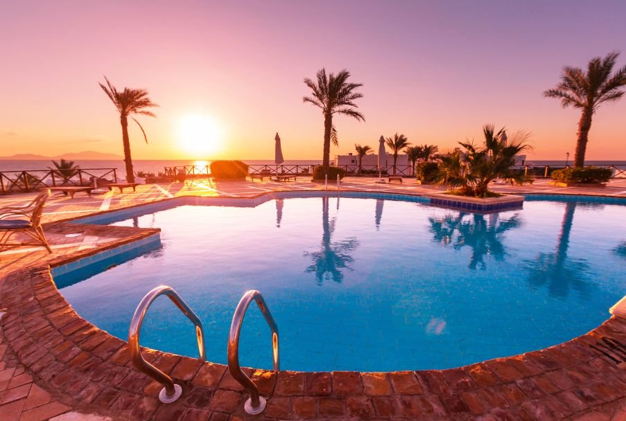 Saltwater pool at sunset with palm trees, clean water, and eco-friendly landscaping near the ocean.